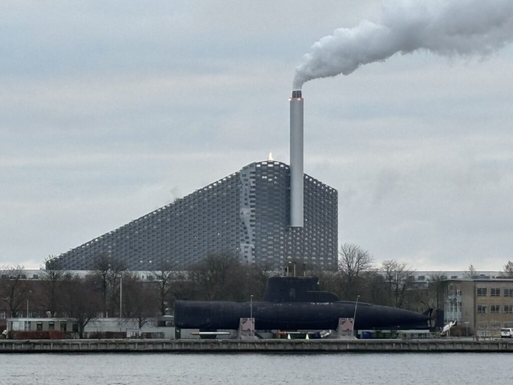 Amager Bakke — affaldsenergianlægget med skibakke — med damp fra skorstenen over havnen.